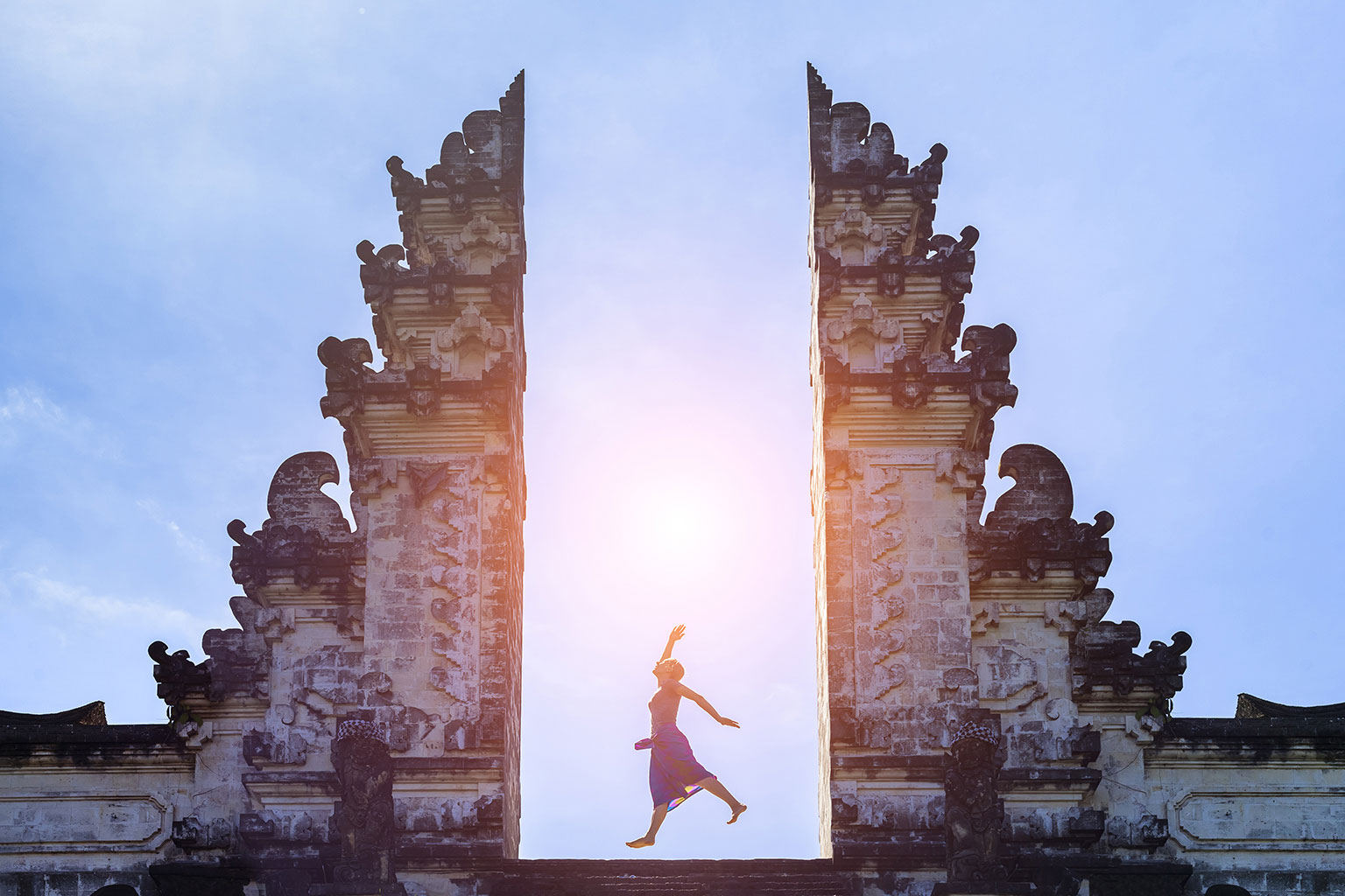 Junge Frau springt in einem Tempel auf Bali